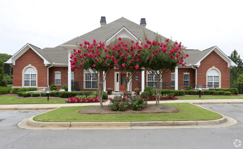 a house with a large flowering tree in front of it at Magnolia Lake Apartments, Carrollton, GA