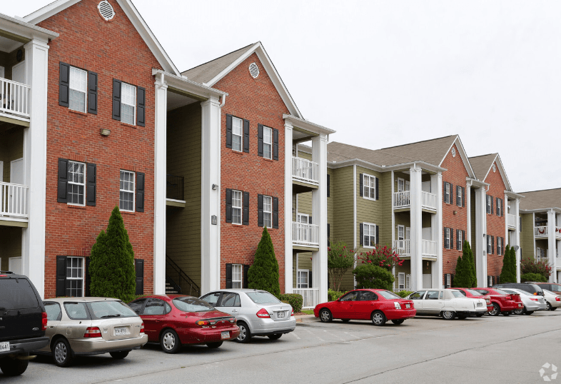 a photo of a street with cars parked in front of an apartment building at Magnolia Lake Apartments, Carrollton