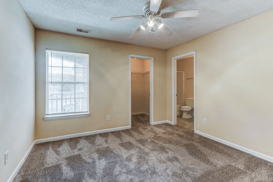 an empty living room with a ceiling fan and a window