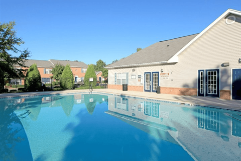 A swimming pool in front of a building with a blue sky in the background.