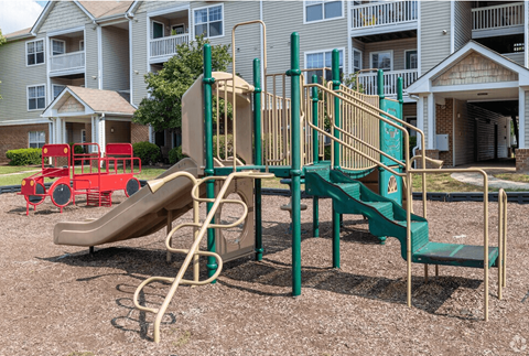 A playground with a green slide and a red slide.