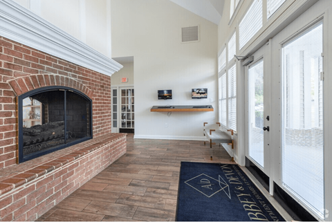 A brick fireplace is in a room with a blue rug on the floor.