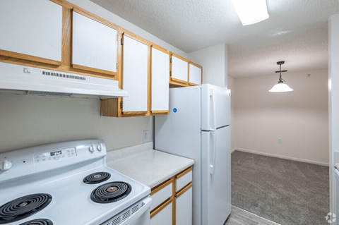 A kitchen with a white stove top oven and a white refrigerator.
