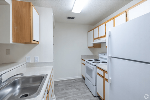 A kitchen with white appliances and wooden cabinets.