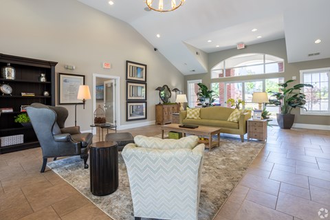 A living room with a grey sofa, a white armchair, a wooden coffee table, and a rug.