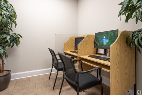 A black chair is in front of a desk with a laptop and keyboard.