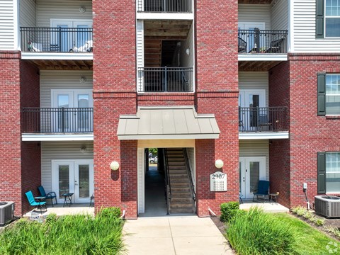 A red brick building with a black metal railing on the balconies.