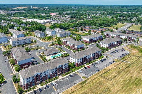 An aerial view of apartment buildings with a parking lot in the foreground.