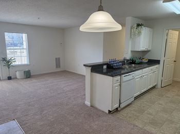 A kitchen with white cabinets and a black countertop.