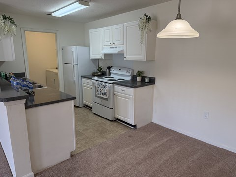 A kitchen with white cabinets and a black countertop.