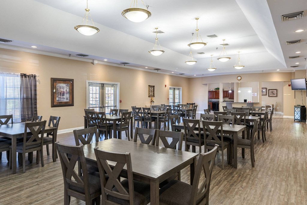 A large room with tables and chairs and a TV.at The Gardens of Stafford, Stafford, VA  