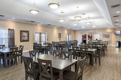 A large room with tables and chairs and a TV.at The Gardens of Stafford, Stafford, VA