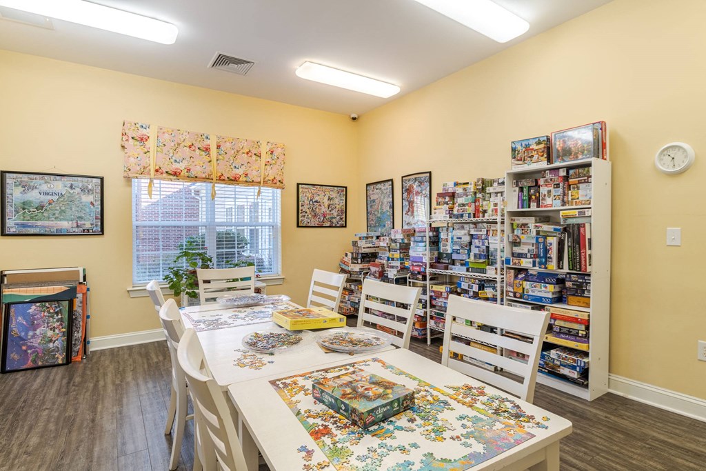 A room with a jigsaw puzzle on the table and a bookshelf filled with books.at The Gardens of Stafford, Stafford 