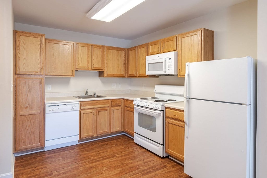 A kitchen with wooden cabinets and white appliances.at The Gardens of Stafford, Stafford, VA  