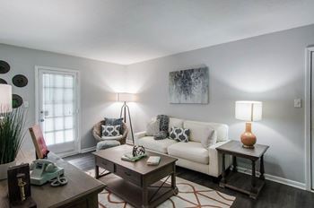 A living room with a white couch, a coffee table, and a lamp.