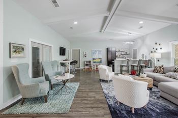 A living room with a white couch, a white chair, a white table, and a white rug.