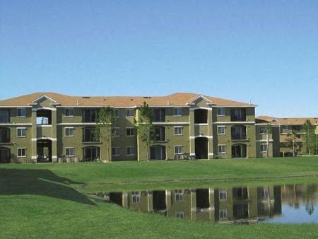 an apartment building with a pond in front of it