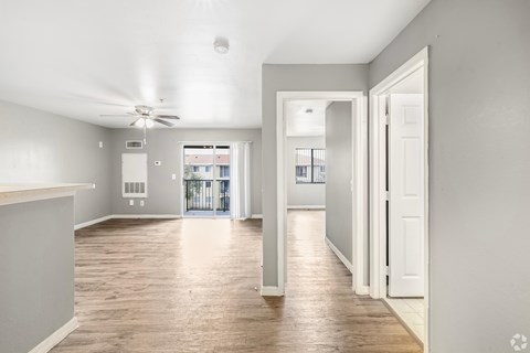 A spacious room with a ceiling fan and wooden flooring.