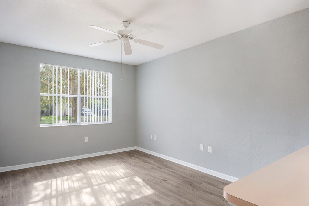 an empty room with a large window and a ceiling fan