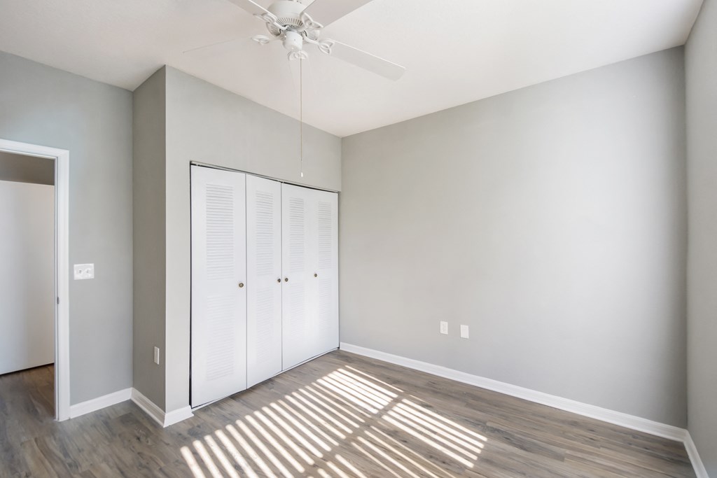 an empty bedroom with a closet and a ceiling fan