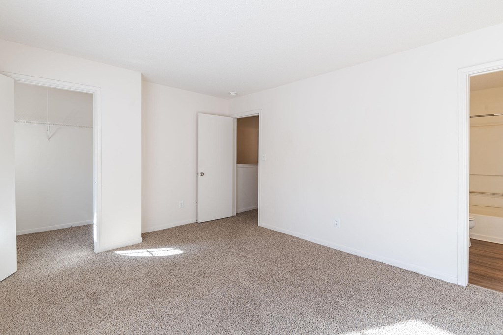 A white room with a carpeted floor and a door.at The Village at England Run, Fredericksburg, VA 22406  