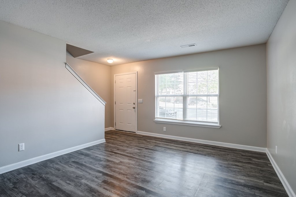 A room with a wooden floor and a window with blinds.