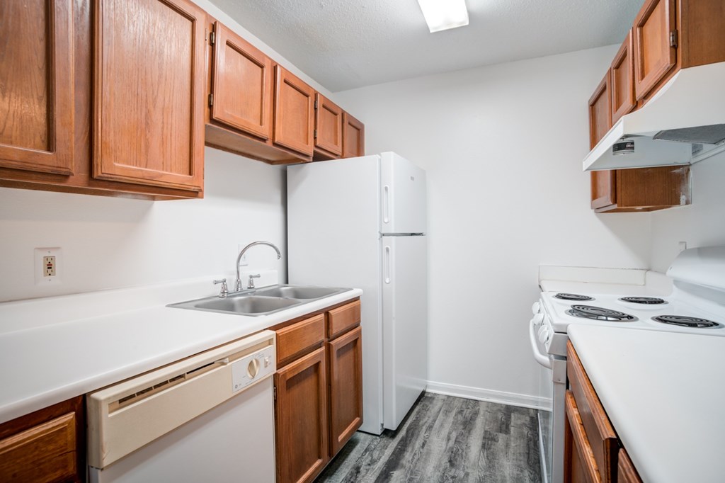 A kitchen with white appliances and wooden cabinets.