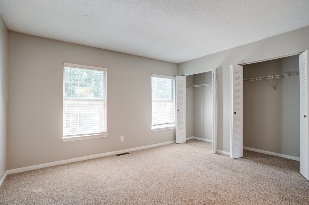 A room with two windows and a carpeted floor.