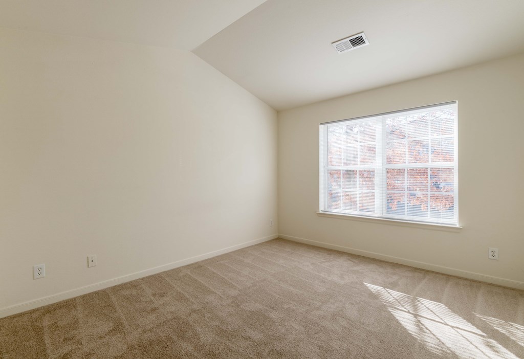A room with a carpeted floor and a window with blinds.