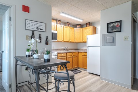 A kitchen with a table and chairs in front of a refrigerator.