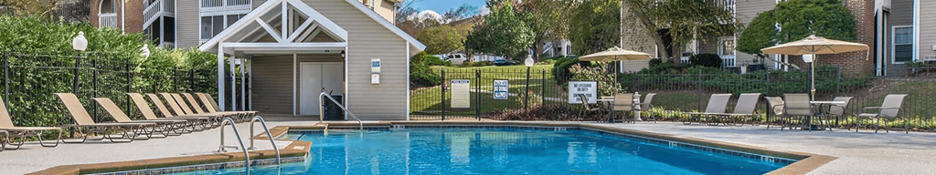a swimming pool with chairs and umbrellas in front of a house at Arbors at Windsor Lake, Columbia, SC  