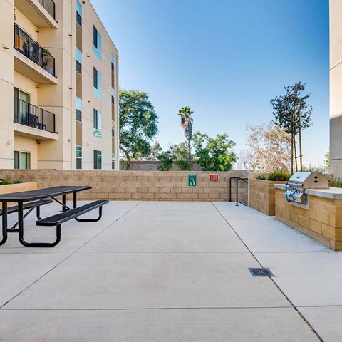 A concrete patio with a table and chairs is surrounded by a wall and a building with balconies.
