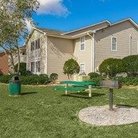 A green bench sits in front of a two-story apartment building.