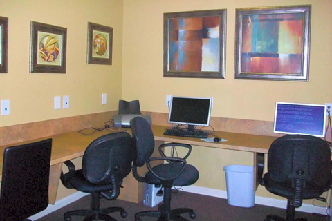 an office with a desk with a computer and chairs