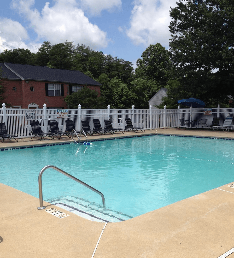a resort style pool with chairs and a fence around it