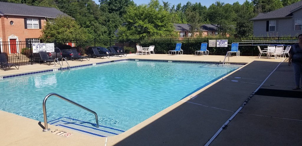 a swimming pool with chairs around it in front of a house
