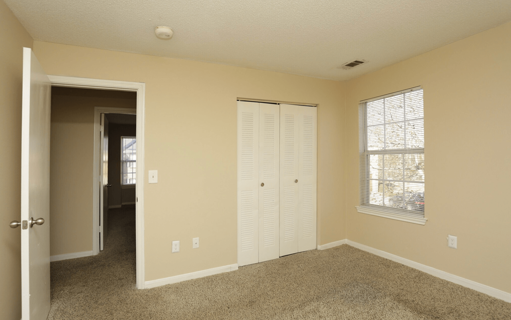 an empty living room with a closet and a window