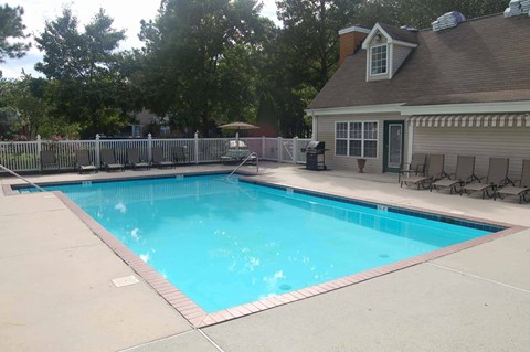 A small residential pool with a deck and a house in the background.