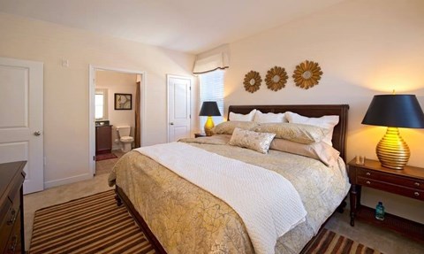 A bedroom with a large bed and a lamp on the side table.