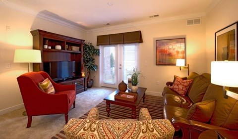 A living room with a red chair and a brown couch.