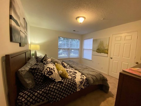 A bedroom with a bed, nightstand, and window.