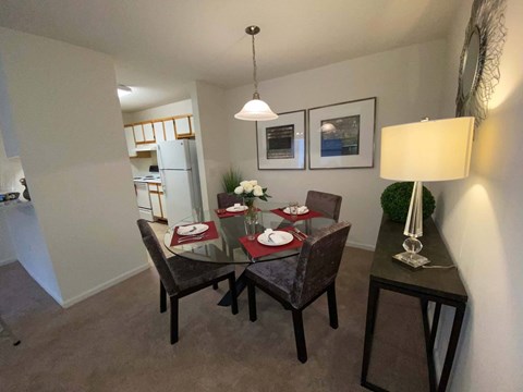 A dining room with a table set for two and a framed picture on the wall.