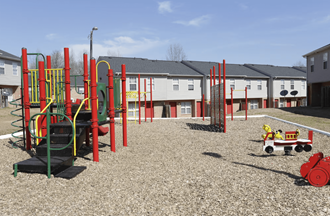 a playground with a wagon and houses in the background