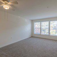 A room with a ceiling fan and carpeted floor.