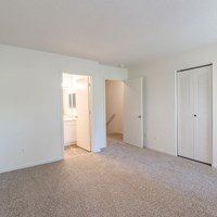 A white room with a carpeted floor and a door on the right.