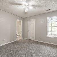 A room with a carpet floor and a ceiling fan.