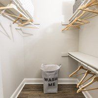 A laundry room with a wash me bucket on the floor.