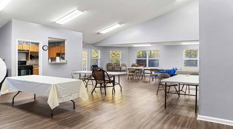 a common room with tables and chairs and a kitchen