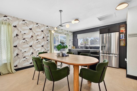 A modern dining room with a round table and green chairs.
