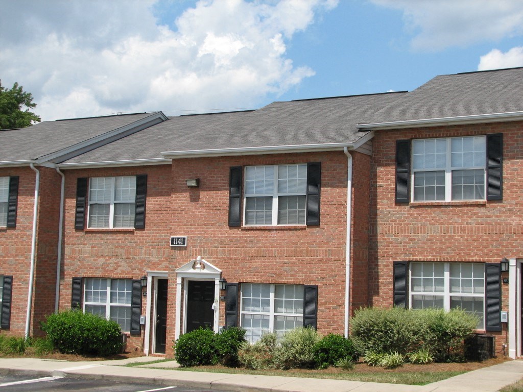 a red brick house with a sidewalk in front of it